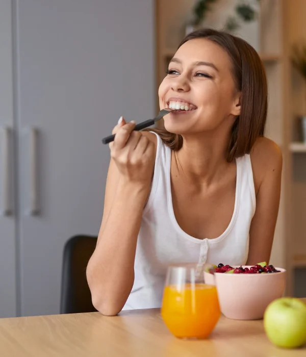 A woman enjoys her fruit bowl and orange juice.