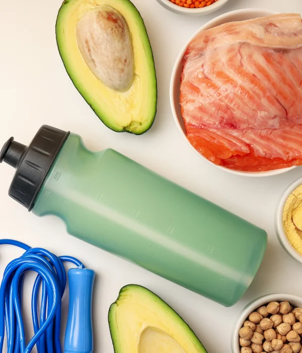 A water bottle positioned next to an avocado and some raw salmon.